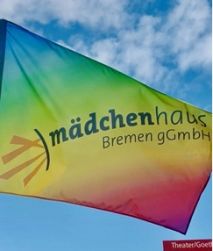 Auf dem Foto ist eine Flagge in Regenbogenfarben mit dem Logo des Mädchenhaus Bremen zu sehen