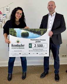 Das Foto zeigt die symbolische Scheckübergabe mit der stellvertretenden Geschäftsführerin  des Mädchenhauses und einem Mitarbeiter der Brauerei Krombacher