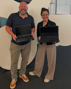 Auf dem Foto sind ein Mitarbeiter der Geschäftsführung von Team Neusta und eine Mitarbeiterin der Geschäftsführung des Mädchenhauses zu sehen. Beide halten einen Laptop in der Hand.