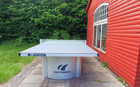 Eine Tischtennisplatte neben einem Gartenhäuschen